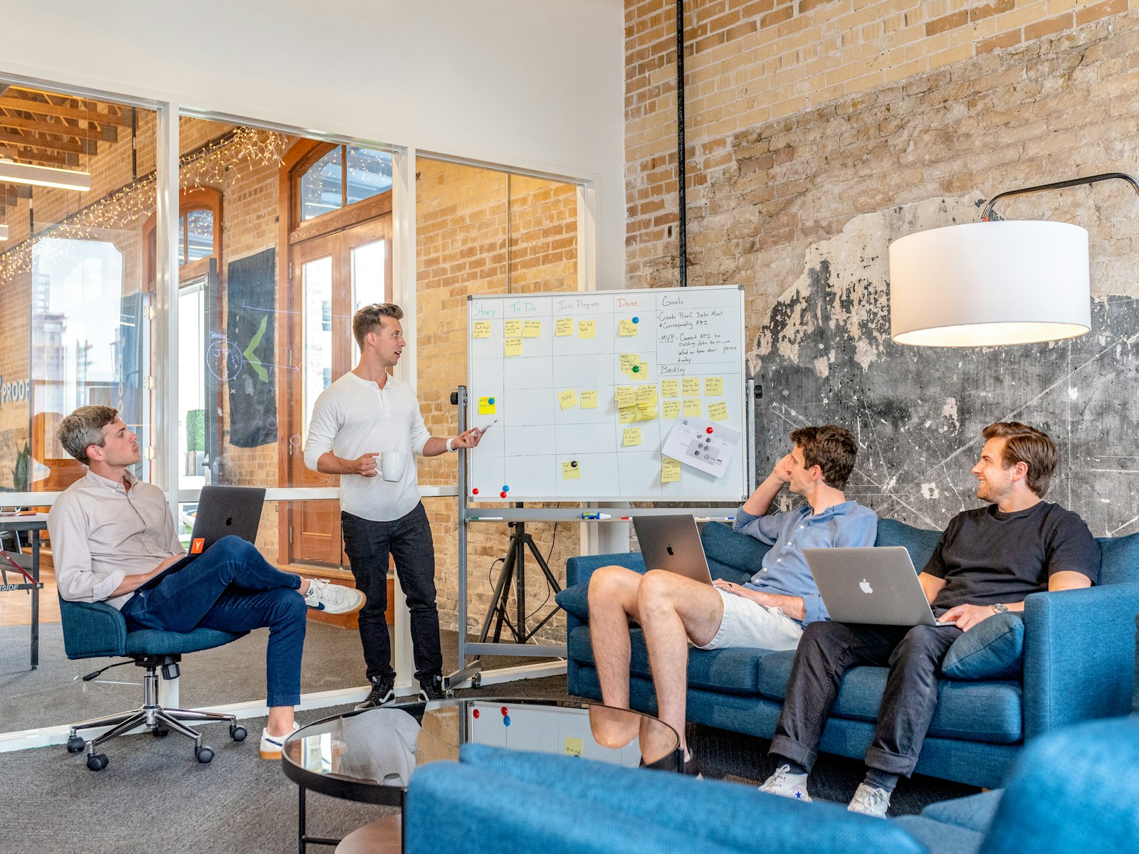 Creative advertising team in a loft studio reviewing ideas on a sticky-note whiteboard